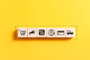 A wooden block featuring icons that represent the concept of ecommerce, prominently displaying the word "ecommerce."