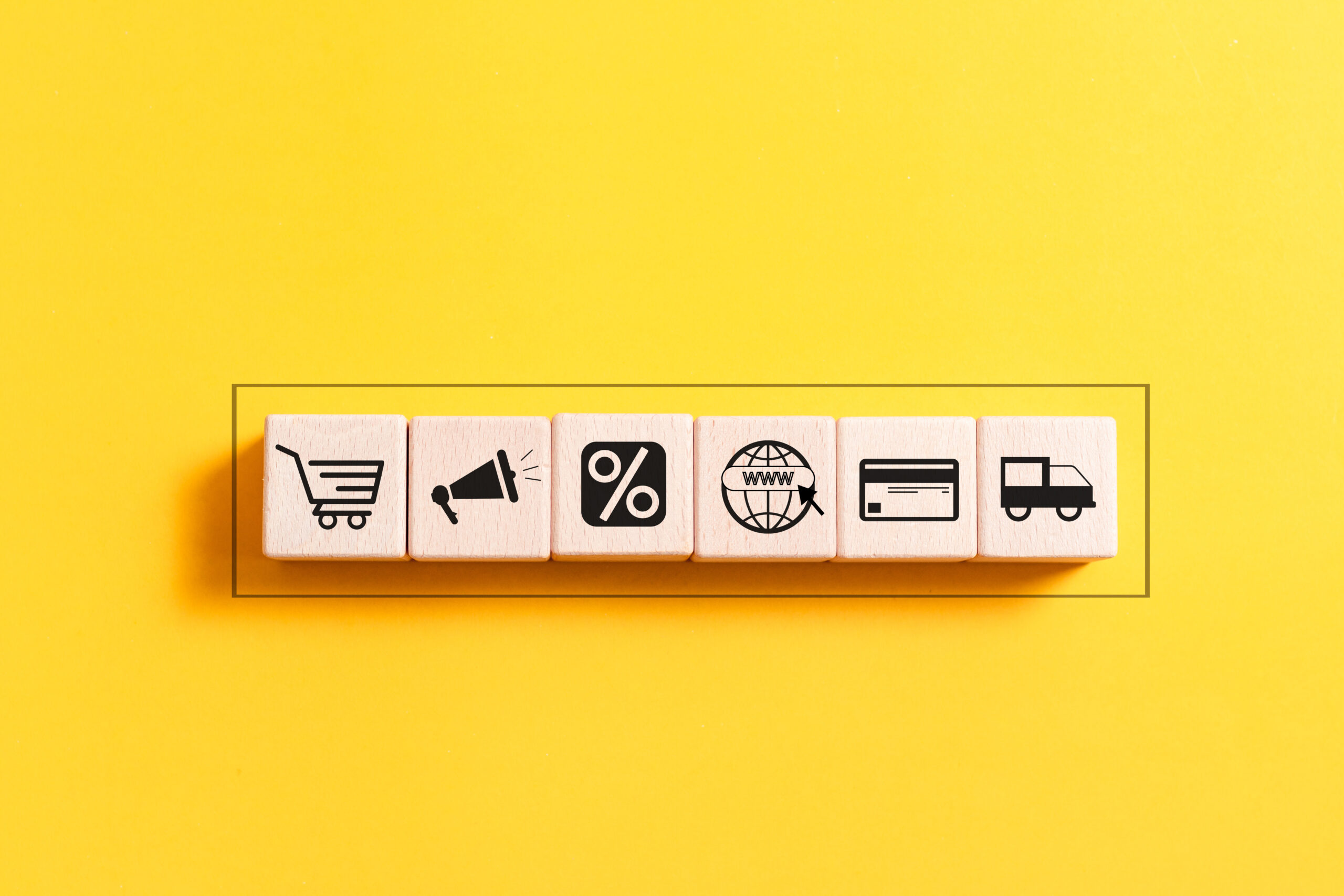 A wooden block featuring icons that represent the concept of ecommerce, prominently displaying the word "ecommerce."