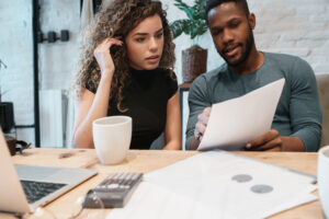Young couple calculating and paying bills on a laptop from home. Couple planning monthly budget.