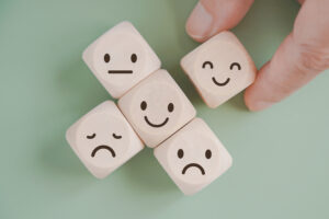 hand selected happy face wood cube and others on green background for customer service evaluation, feedback, satisfaction survey or mental heath concept