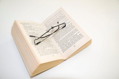 Open paperback book and reading glasses