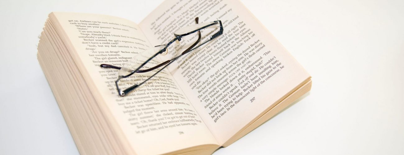 Open paperback book and reading glasses