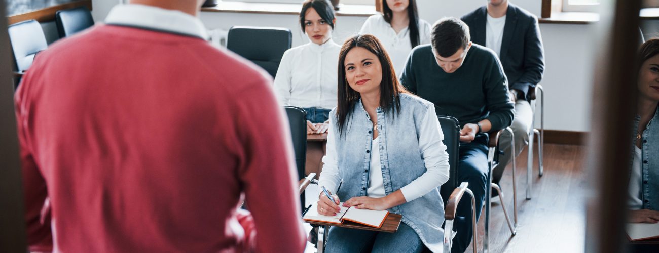 In red shirt. Group of people at business conference in modern classroom at daytime