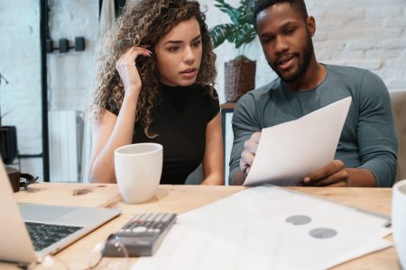 Young couple calculating and paying bills on a laptop from home. Couple planning monthly budget.