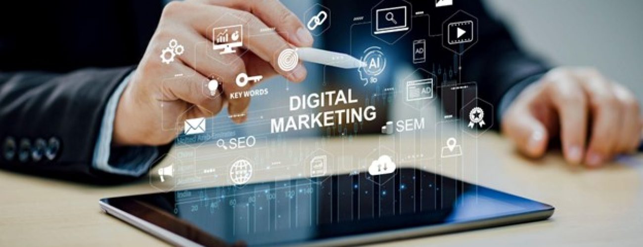 there is a holographic touchscreen with the words digital marketing and tech symbols around it. there is a tablet underneath it with the hand of a man in a suit touching the projected screen