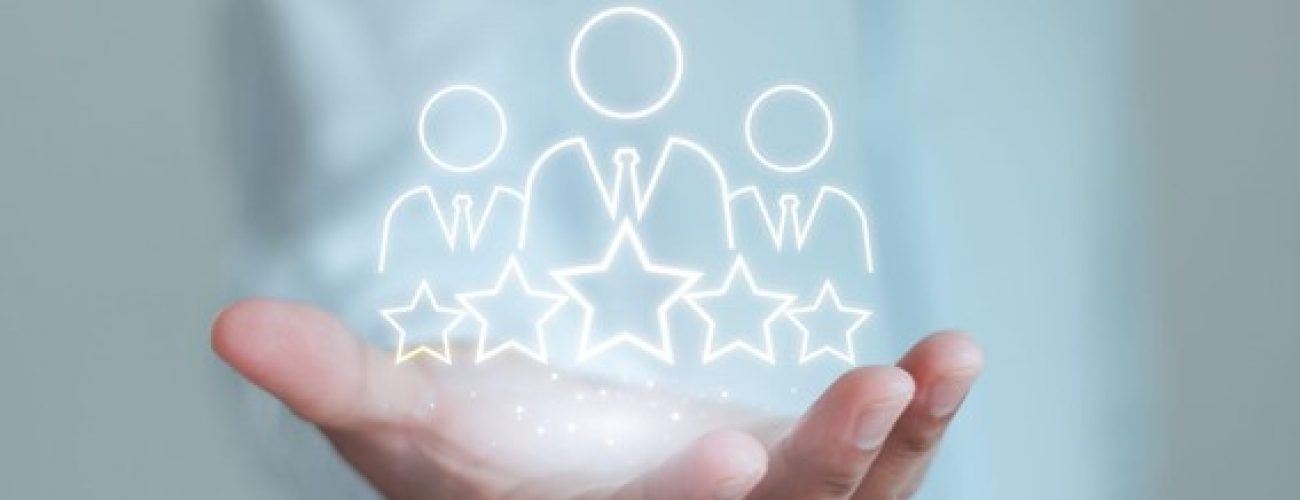 there is a hand in the center and the body is blurred out in the background. in the hand are three figures with five stars wrapped around them and they are glowing.