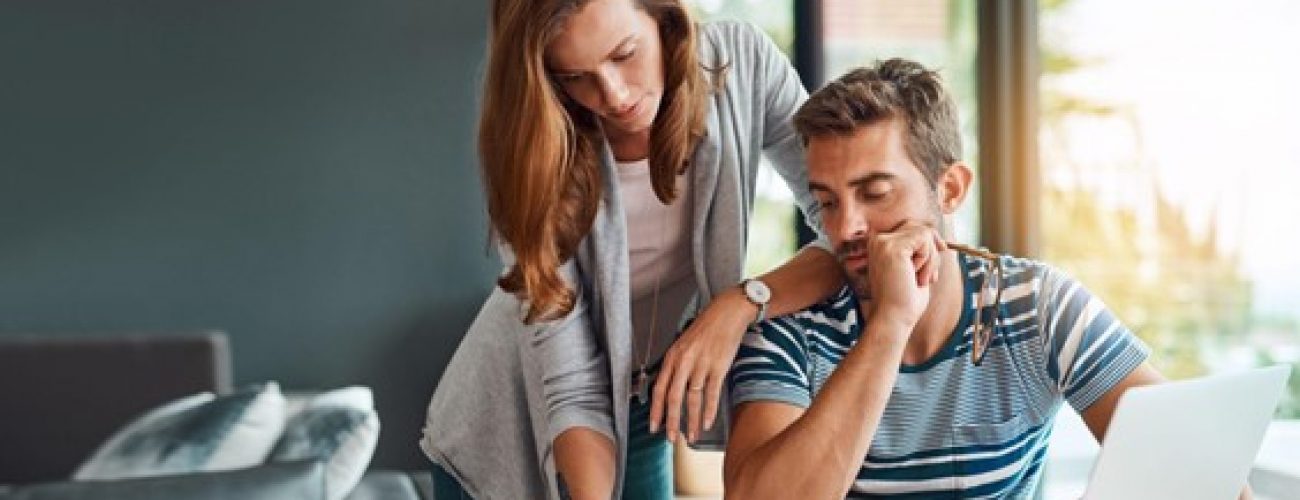 Picture1 woman standing over a man who is sitting down. they are both looking down at papers.